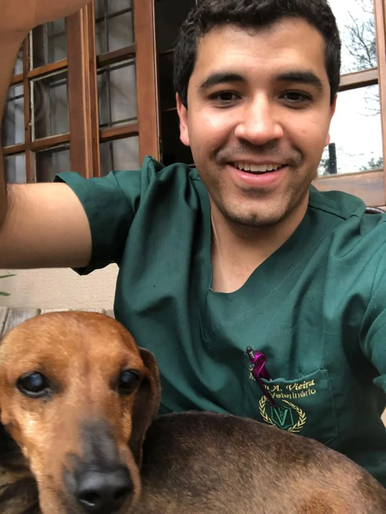 Dr. Maicon Vieira com cão dachshund em consulta domiciliar